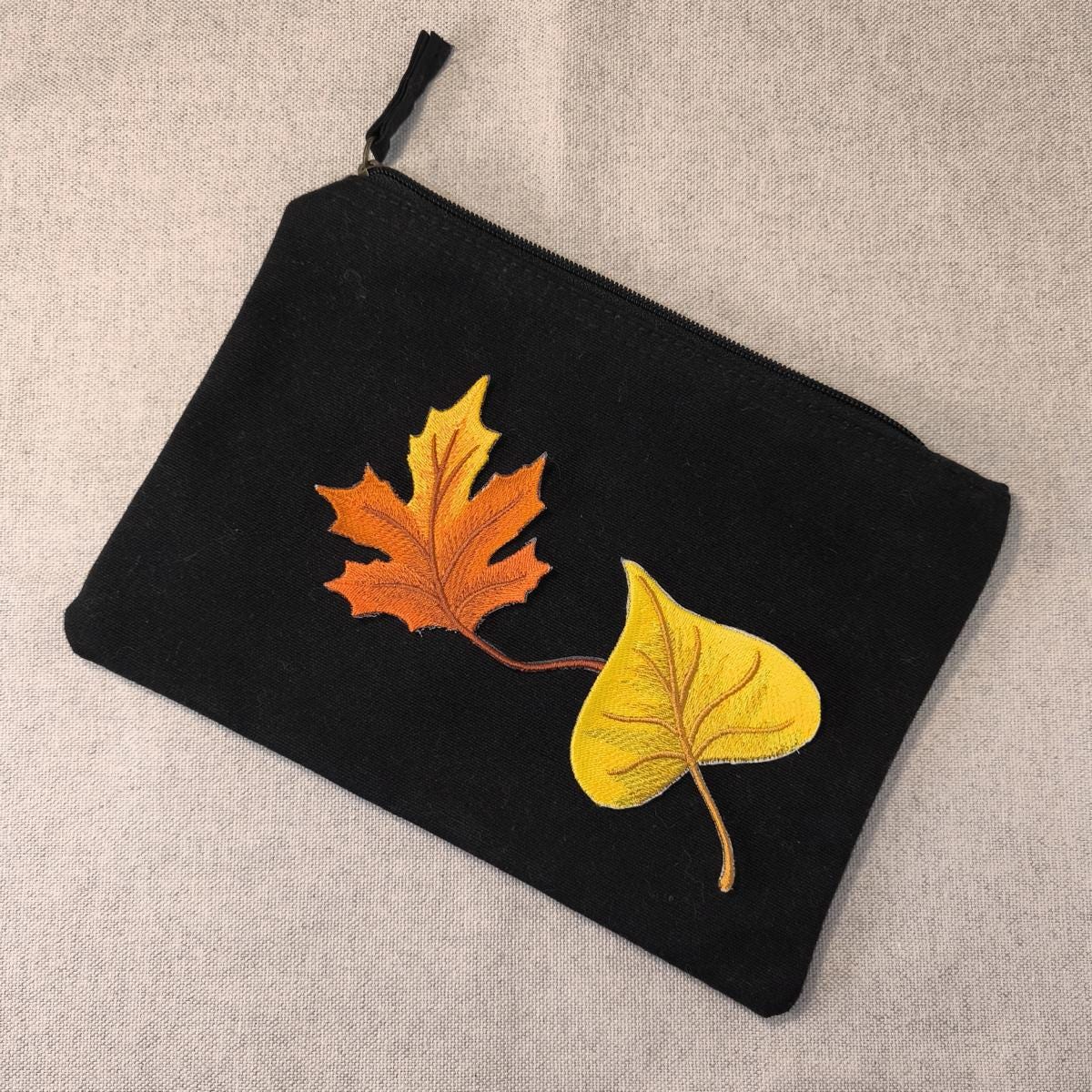 Ein Stück Pappel Blatt und ein Stück Ahornblatt Aufnäher zum aufbügeln auf einem schwarzen Etui als Beispiel auf einem neutralen Hintergrund