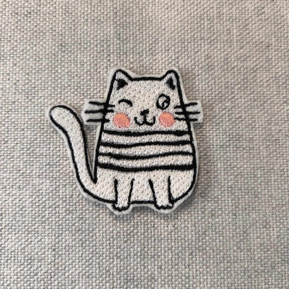 Eine Nahaufnahme der Zwinkernde Katze Aufnäher.