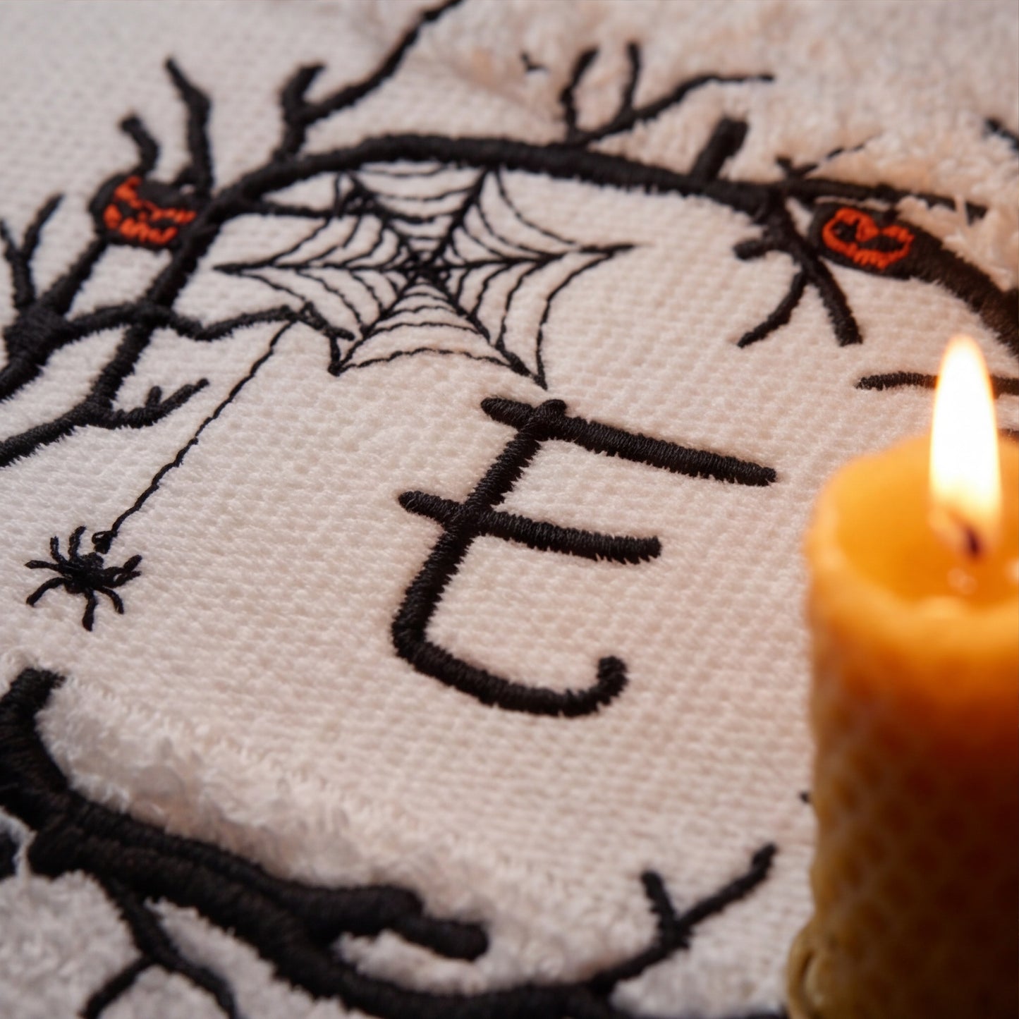 Weißes besticktes Halloween-Handtuch mit Monogramm E, dekoriert mit Kürbissen, Herbstblättern und Kerzen