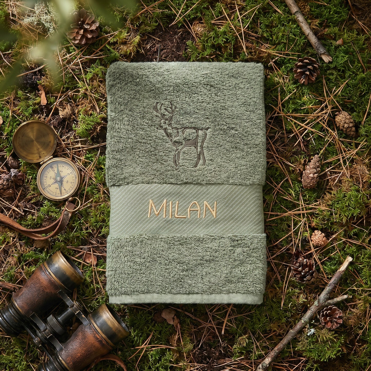 Olivgrünes besticktes Handtuch mit einem stolzen Hirsch-Motiv und dem Namen Milan in goldener Schrift.