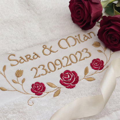 Nahaufnahme der hochwertigen goldenen Garnstickerei Sara & Milan 23.09.2023 und der roten Stickrosen auf flauschigem Baumwollstoff.