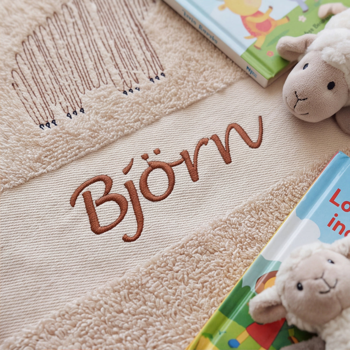 Nahaufnahme der hochwertigen braunen Namensstickerei Björn und der Bärenkontur auf dem flauschigen Baumwoll-Handtuchstoff.