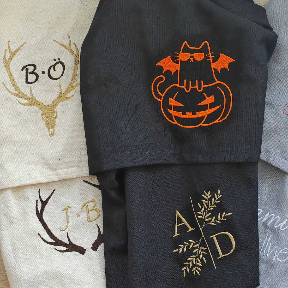 Auswahl bestickter Baumwoll-Geschirrtücher mit Hirschschädel, Geweih-Monogramm J.B., orangefarbener Halloween-Katze und Gold-Initialen A D