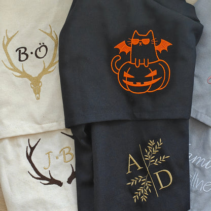 Auswahl bestickter Baumwoll-Geschirrtücher mit Hirschschädel, Geweih-Monogramm J.B., orangefarbener Halloween-Katze und Gold-Initialen A D