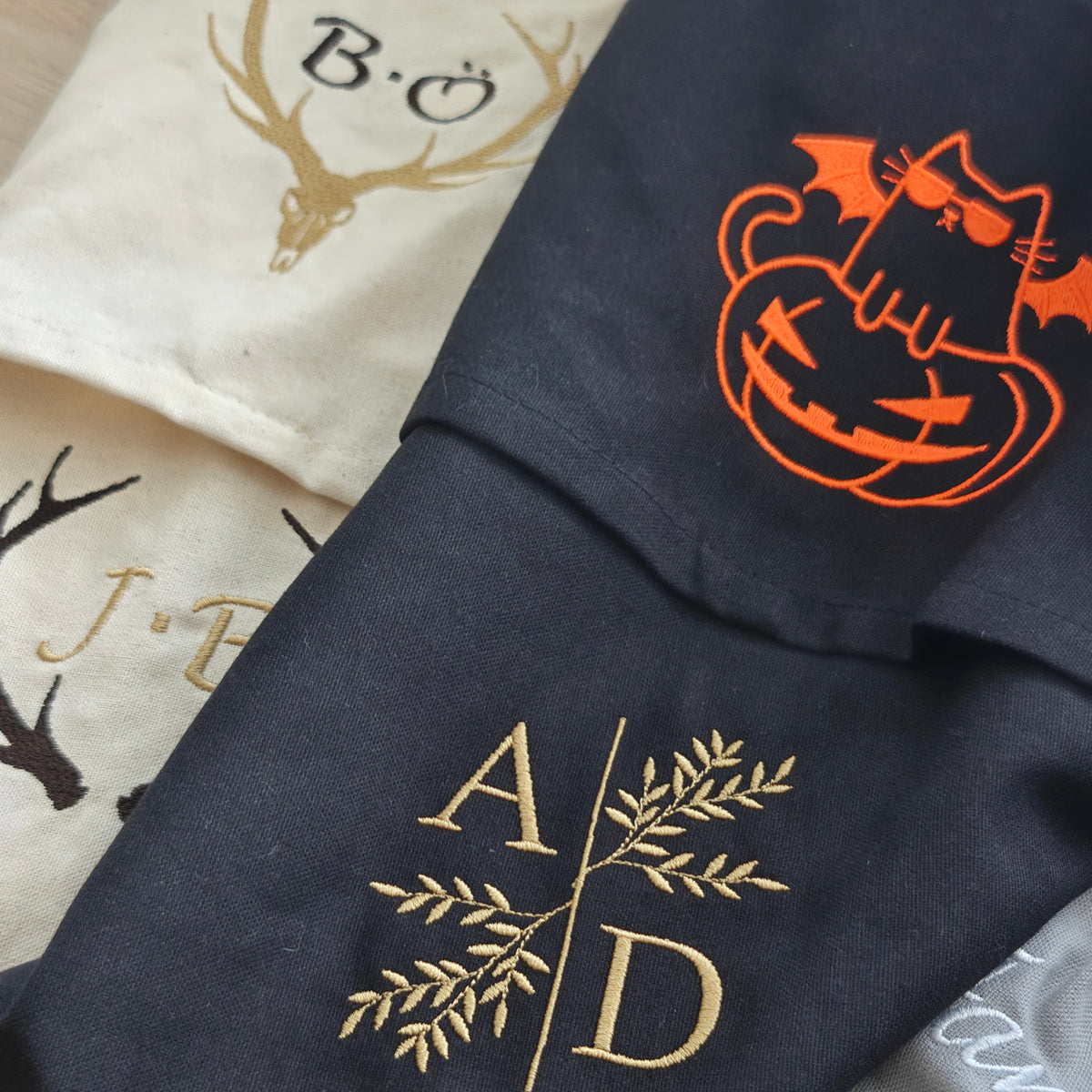 Auswahl bestickter Baumwoll-Geschirrtücher mit Hirschschädel, Geweih-Monogramm J.B., orangefarbener Halloween-Katze und Gold-Initialen A D